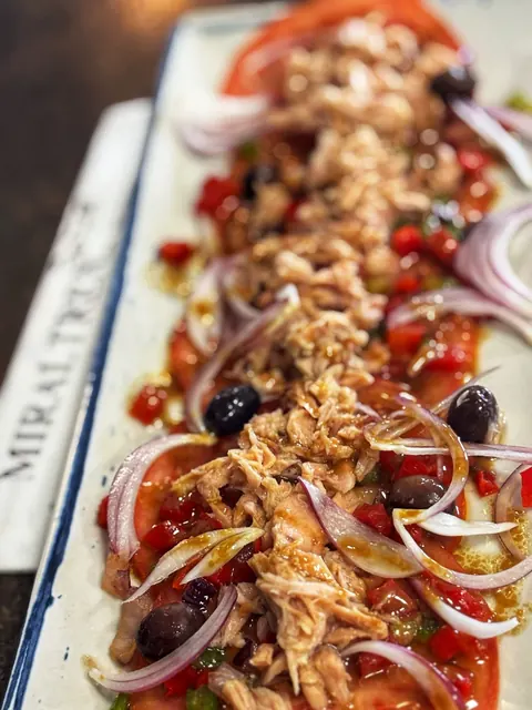Ensalada de tomate y atún presentada en un plato alargado en el MIRALTREN