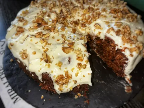 Part de carrot cake, glaçage crémeux et noix